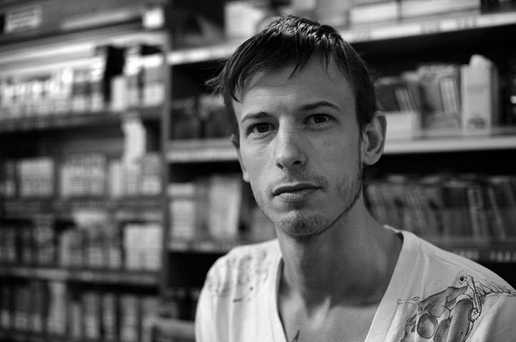 Camera Club Portraits: A man in front of his papers stall in the city