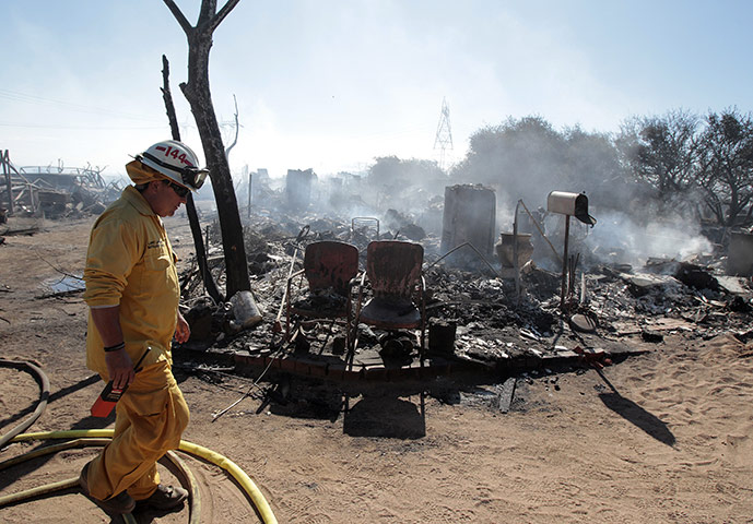 24 hours: Hesperia, California, USA: A man walks past a home burned by a wildfire