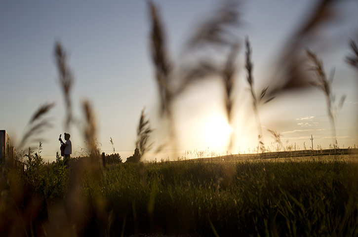 Oil in North Dakota: A man plays his guitar in a field next to a temporary housing unit