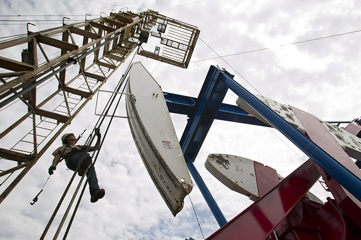 Oil in North Dakota: Ben Shaw hangs from an oil derrick