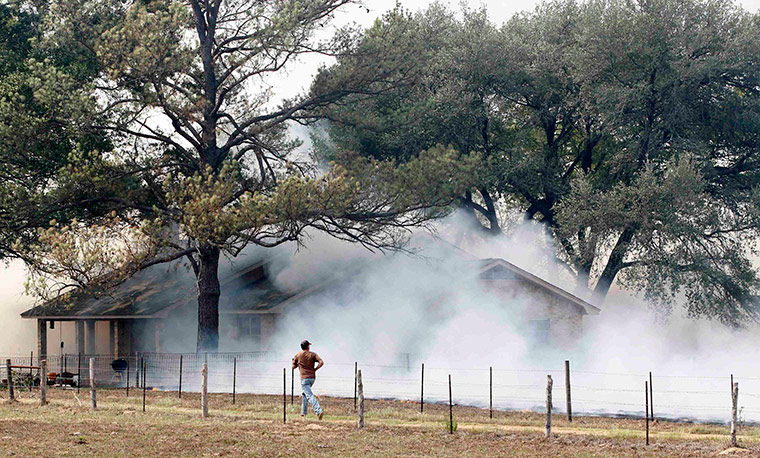 Texas Wildfires: Man runs towards a home as smoke engulfs the house near Bastrop, Texas