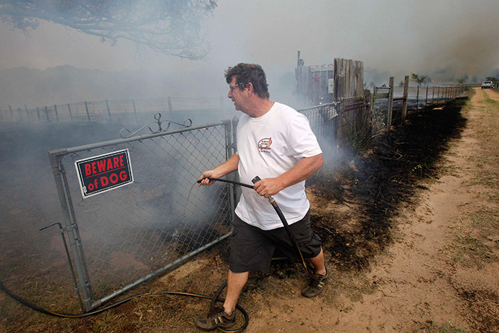 Texas Wildfires: Man drags a water hose in an attempt to prevent flames reaching home, Texas