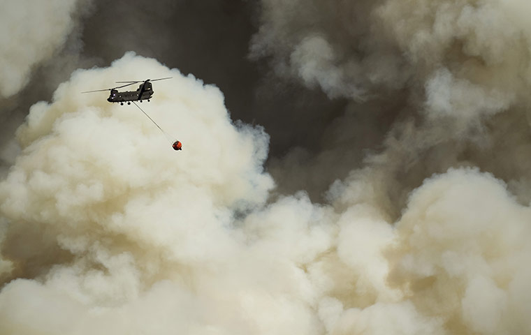 Texas Wildfires: A firefighting helicopter surrounded by plumes of smoke, Bastrop, Texas