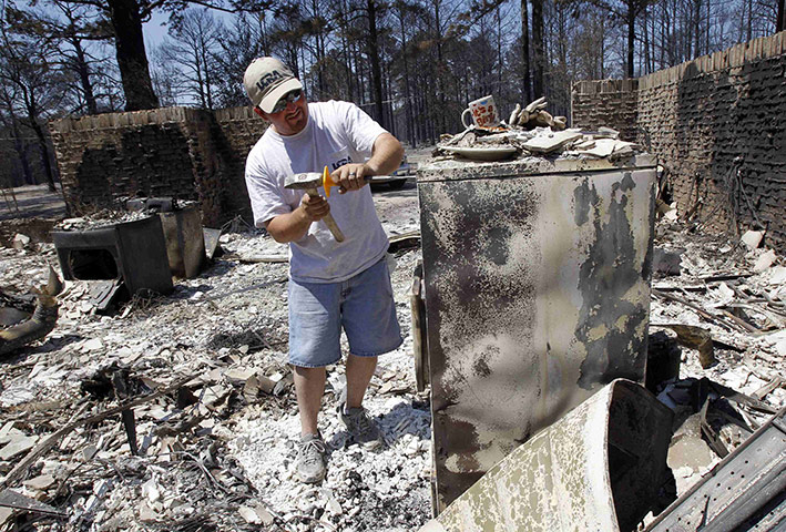 Wildfires damage: A man uses a chisel and hammer to open a fireproof cabinet