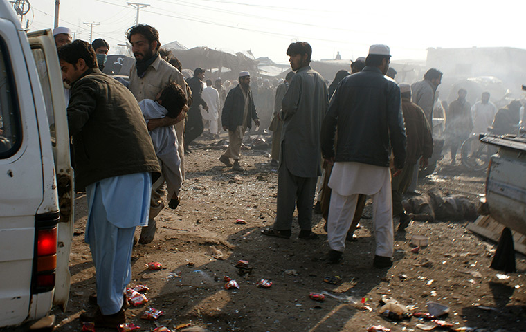 Pakistan bombing: A man carries an injured person to a vehicle 