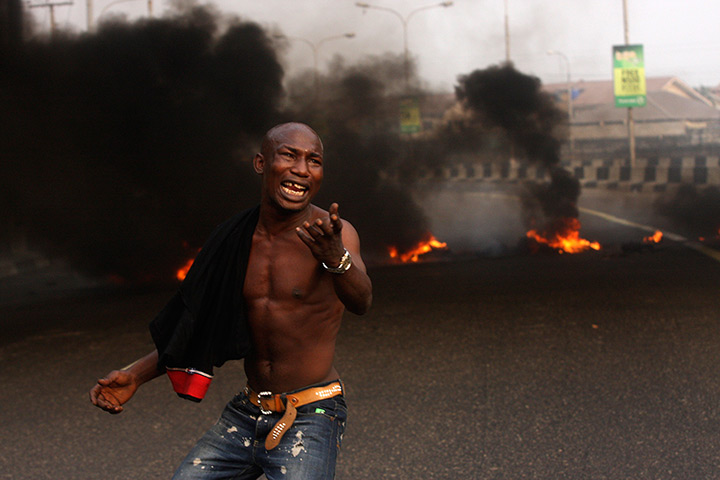 Nigeria protests: A angry youth protests in front of a burning barrier 