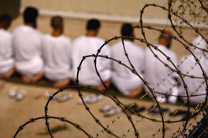 Inside Guantanamo: a group of detainees kneels during an early morning Islamic prayer 