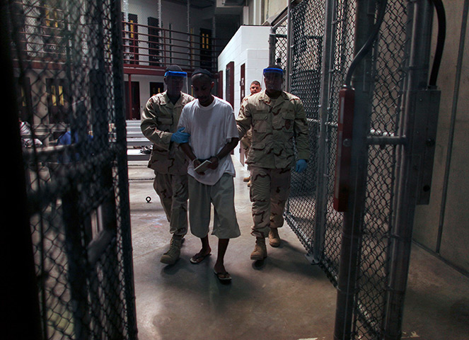 Inside Guantanamo: A Guantánamo detainee carries a workbook as he is escorted by guards