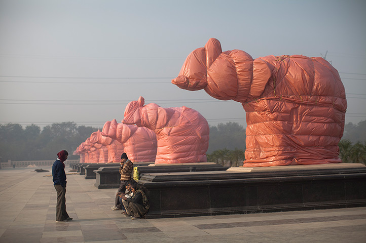 24 hours in pictures: A worker stands under covered elephant statues at the Ambedkar Park
