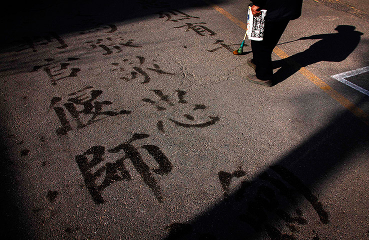 24 hours in pictures: A man writes Chinese characters on a footpath, Beijing