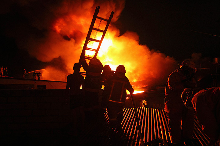 24 hours in pictures: A firefighter carries a ladder at a  warehouse in Manila