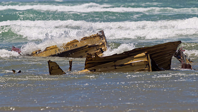 Rena breaks up: A shipping container in the waves after being washed ashore on Waihi Beach