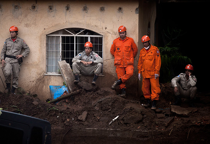 24 hours in pictures: Firefighters wait as they watch a bulldozer digs a mudslide, Brazil