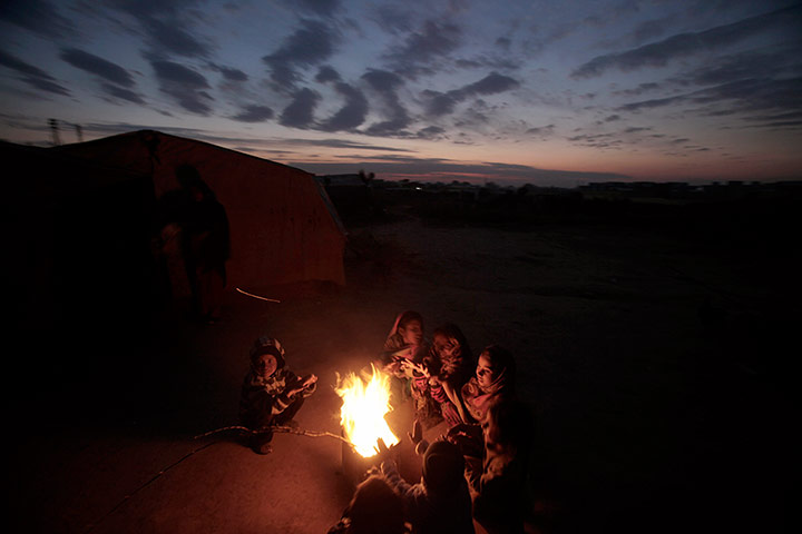 24 Hours: Pakistani children sit around a fire during a cold evening