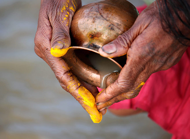 Ganges: A devotee empties a vessel while praying