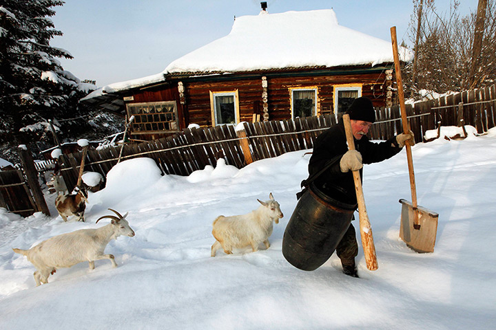 24 hours: Pravy, Russia: A man carries a barrel of snow