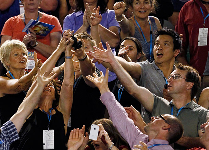 Autralian Open Roundup: Members of the crowd reach for Roger Federer of Switzerland's headband 
