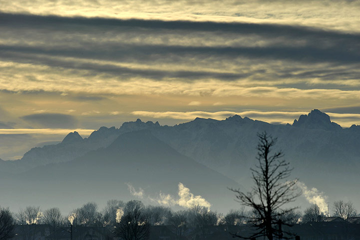 24 hours in pictures: Smoke rises from chimneys in  in front of the Chiemgauer mountains 