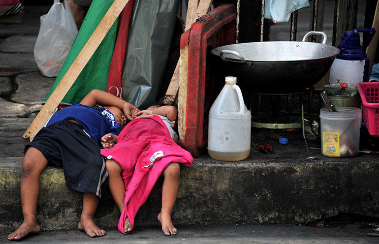 24 hours in pictures: Homeless children sleep beside a frying pan  in Manila