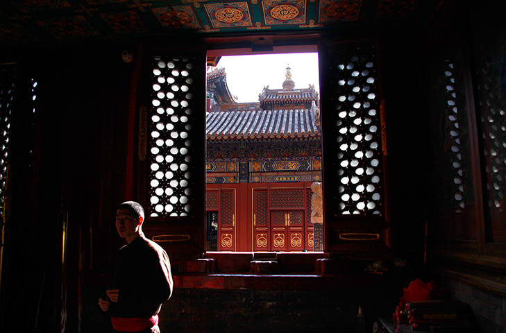24 hours: Beijing, China: A monk watches devotees pray at one 