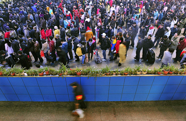 China Spring Festival: A security guard patrols as passengers queue up to buy bus tickets