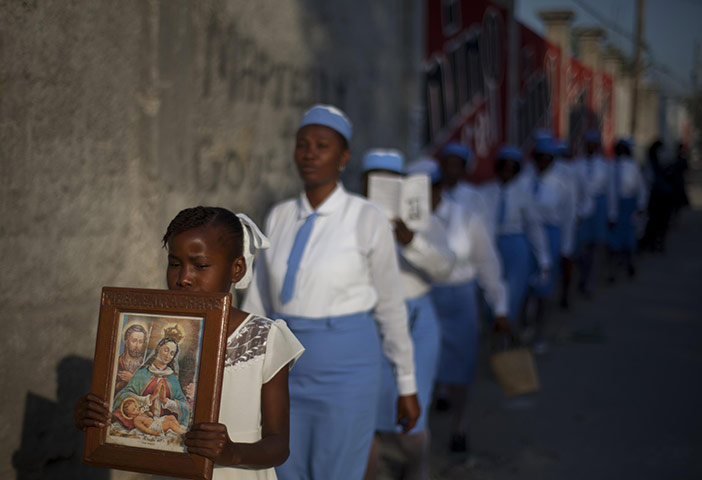 24 hours : Port-au-Prince, Haiti: A girl carries a religious image in a procession