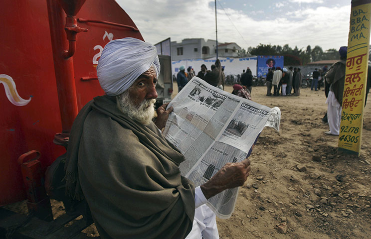 24 hours in pictures: Mukhtsar, India: An Indian man reads a newspaper near an election rally