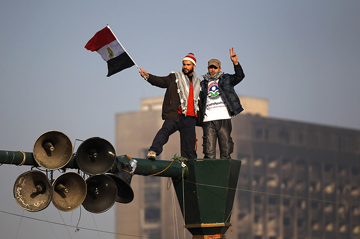 Egypt rally: Men stand on a post as Egyptians gather in Tahrir Square 