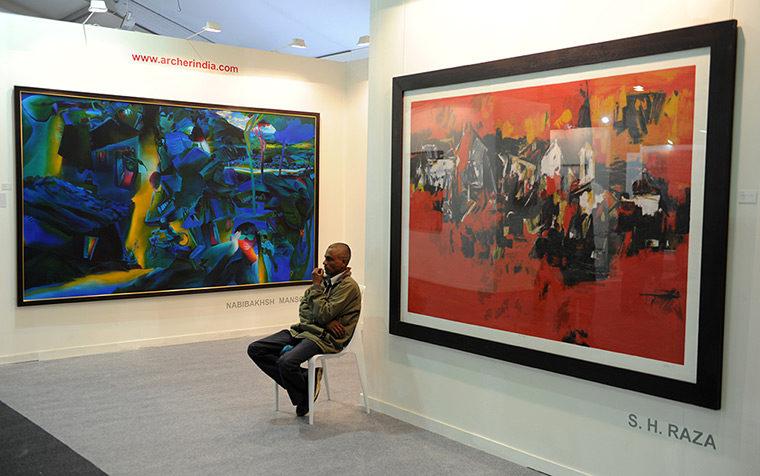 India art fair: A guard sits near a painting by Indian artist S.H. Raza 