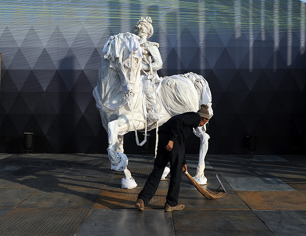 India art fair: An employee sweeps around a sculpture by Indian artist Siddharth Karawal 