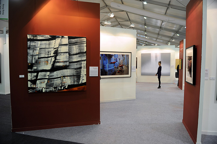 Delhi art fair: An exhibitor stands between stalls near a photograph by Steve McCurry 