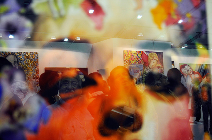 Delhi art fair: Visitors are reflected in the glass of a painting on the opening night