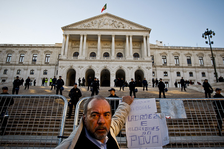 Week in business: A protester stands in front of the Portuguese parliament