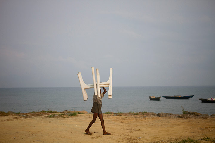 24 Hours: A child carries plastic tables to be placed at the fish market in Bata