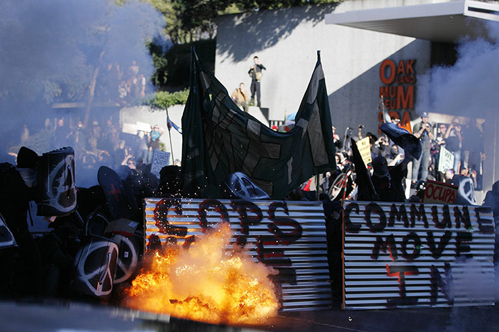 Occupy Oakland: Occupy Oakland demonstrators shield themselves from tear gas