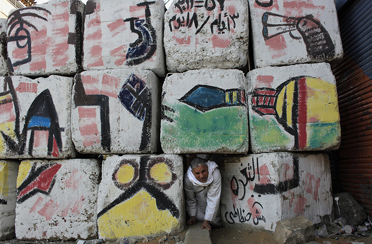 24 hours in pictures: A man crawls through a gap the barrier near tahrir square