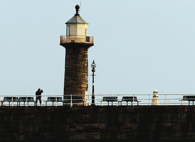 stormy weather in uk: A man holds on to his hat on the pier in Whitby 