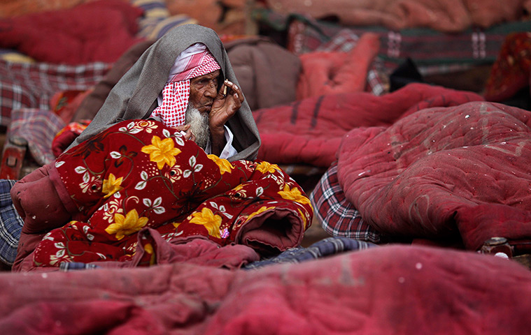 24 hours in pictures: An old man smoke a beedi wrapped in a rented quilt, New Delhi