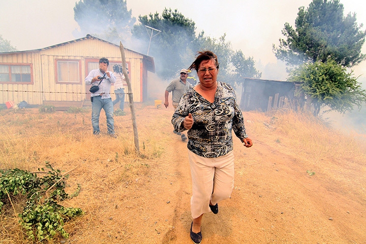 Forest fires in Chile: A woman runs from a forest fire