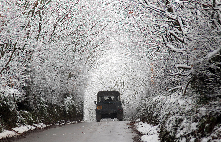 UK weather: A Land Rover drives in snow covered trees near Dulverton on Exmoor