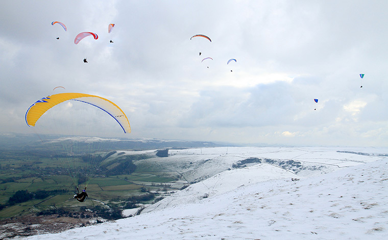 UK weather: Paragliders take to the chilly skies over Mam Tor, Peak District