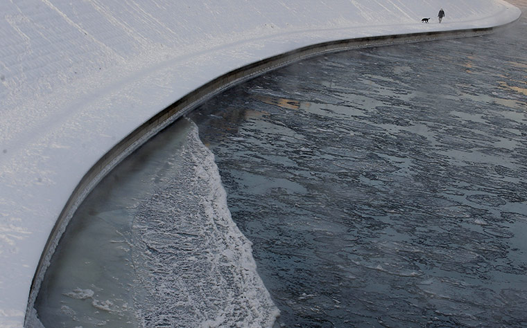 24 hours in pictures: A man walks his dog along the frozen river Neris