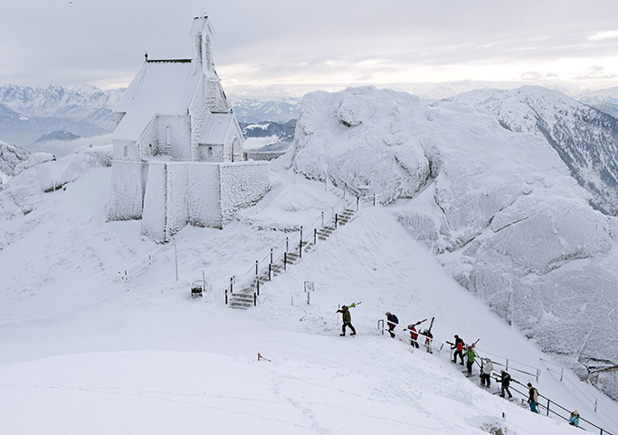 World weather: A group of skiers walks up to the snow covered Wendelstein church, Germany