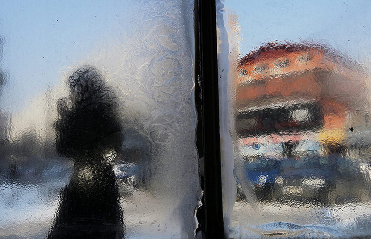 World weather: Woman seen through the frosted window of a subway entrance, Bucharest