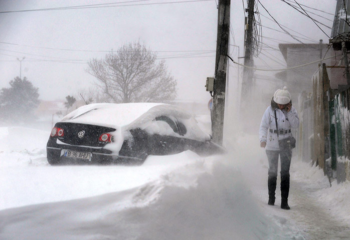 World weather: A woman walks in a blizzard in the village of Catelu, Romania