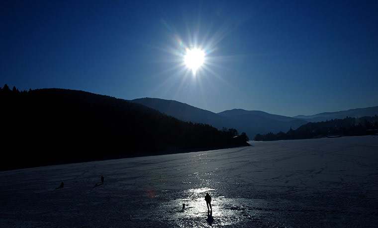 World weather: A fisherman on the ice as he watches for fish on a frozen lake, Bulgaria