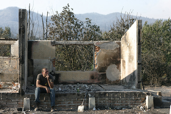 Chile forest fire: A man rests amid the debris of his house, destroyed by a fire, Chile