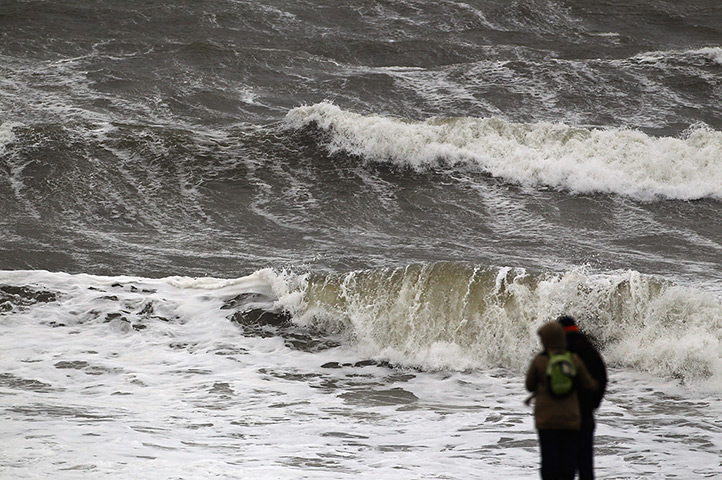 UK weather: A couple walk in front of a rough seas in Woolacombe
