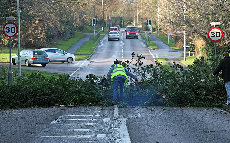 UK weather: A workman with a chainsaw works to remove a fallen tree in Royston