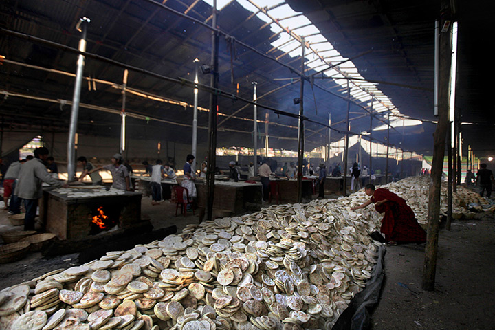 FTA: Altaf Qadri: A young Buddhist monk picks up a bread from a pile